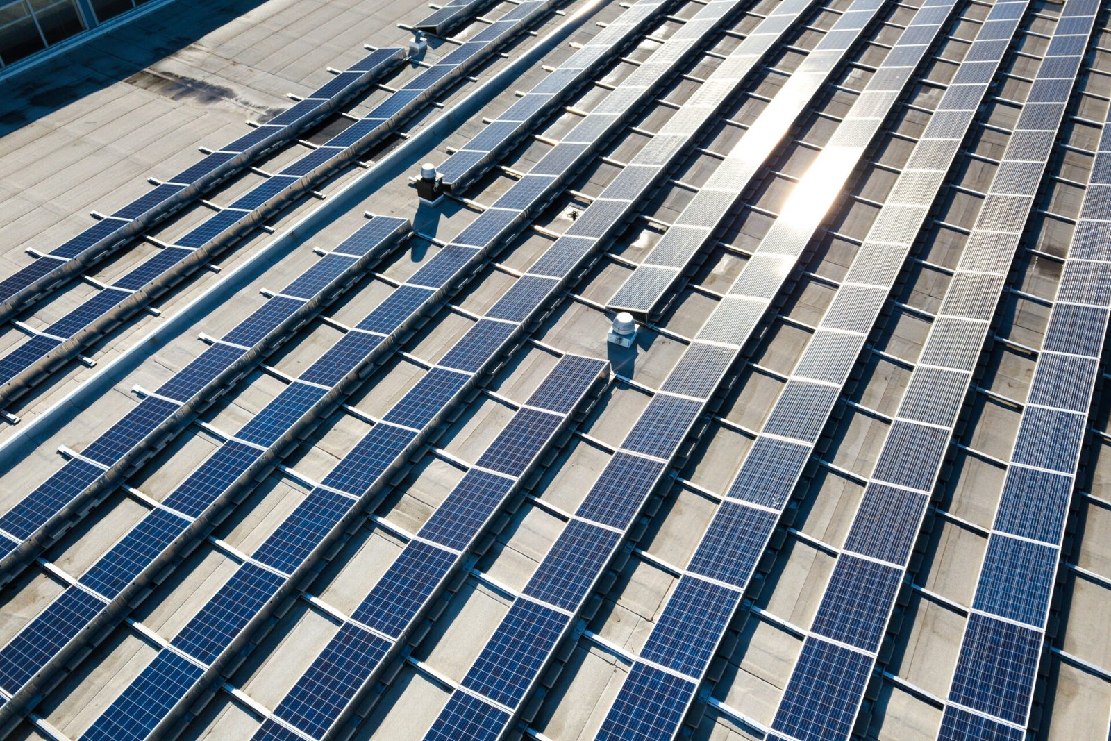 Aerial view of many photo voltaic solar panels mounted of industrial building roof.