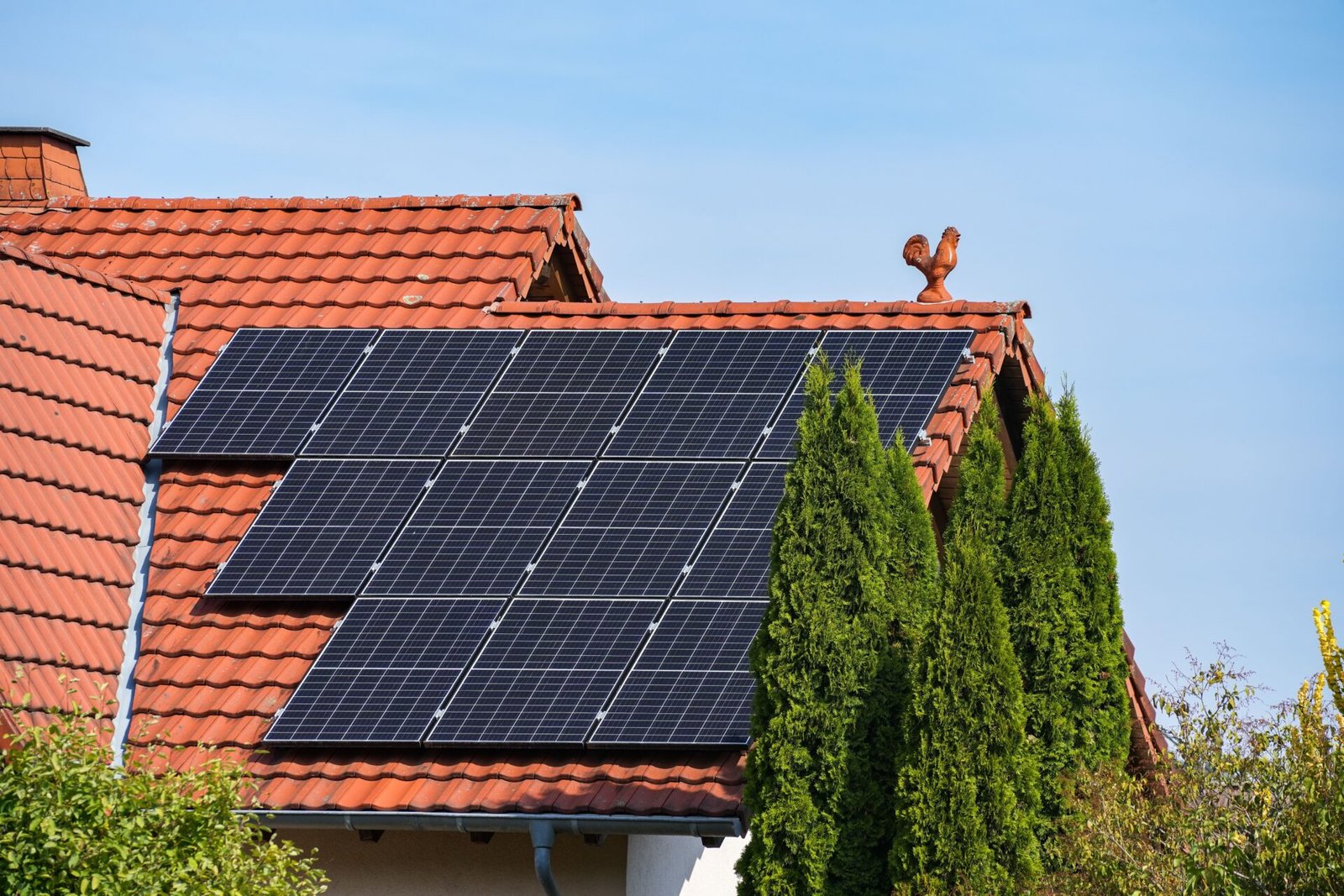 An aerial view of solar panels on the brownish-orange roof of a building
